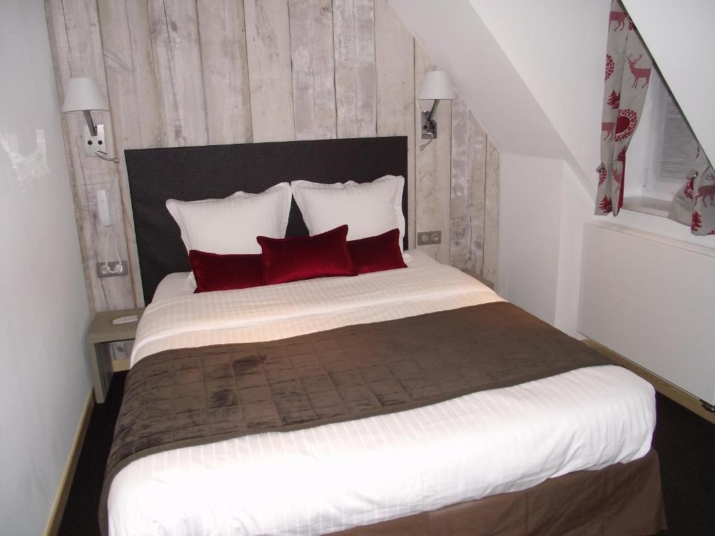 a bedroom with a large bed with red pillows at Hôtel Panorama in Munster