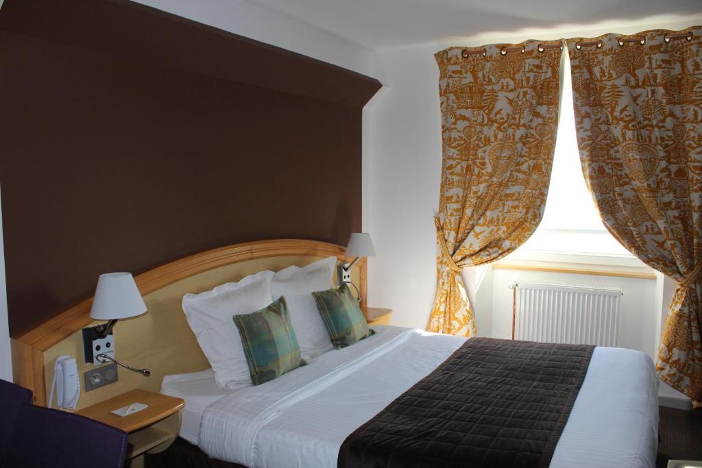 a bedroom with a bed and a window with curtains at Hôtel Panorama in Munster