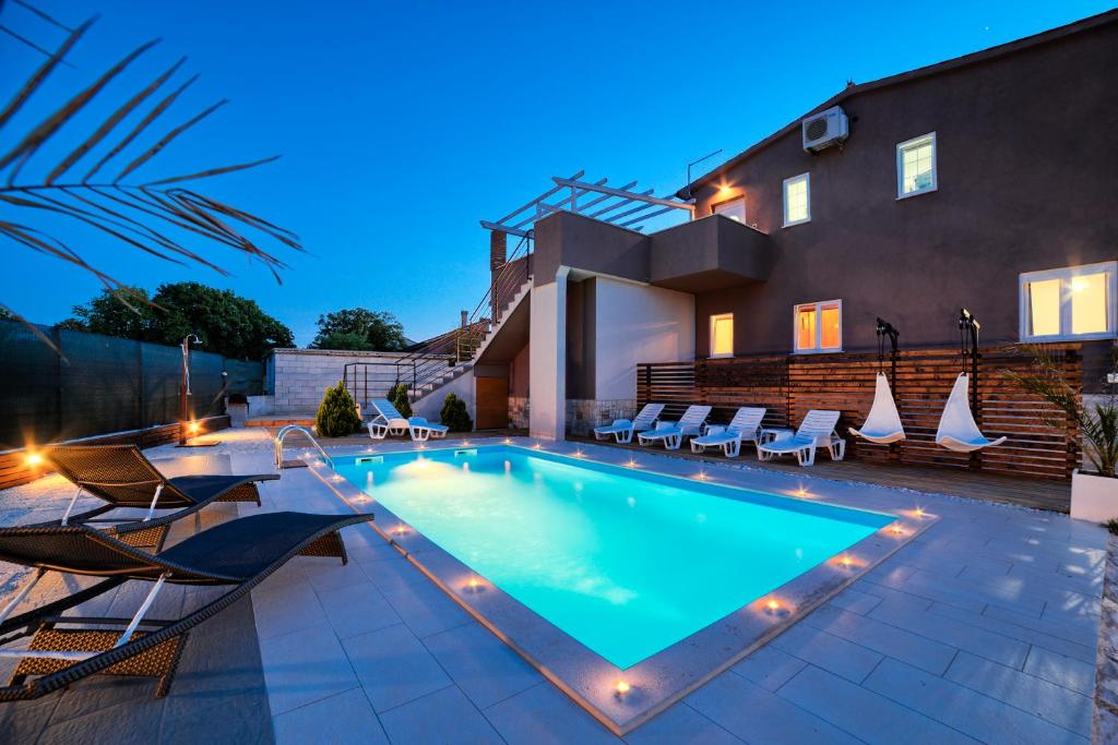 a swimming pool with chairs and a house at Stylish & luxury villa with pool, biliard, extra pool heating available in Pula