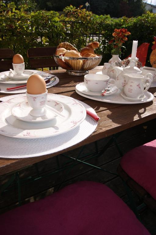 a wooden table with eggs on plates and cups at Gästehaus &#39;Alte Bäckerei&#39; Kaffeehaus in Großbundenbach