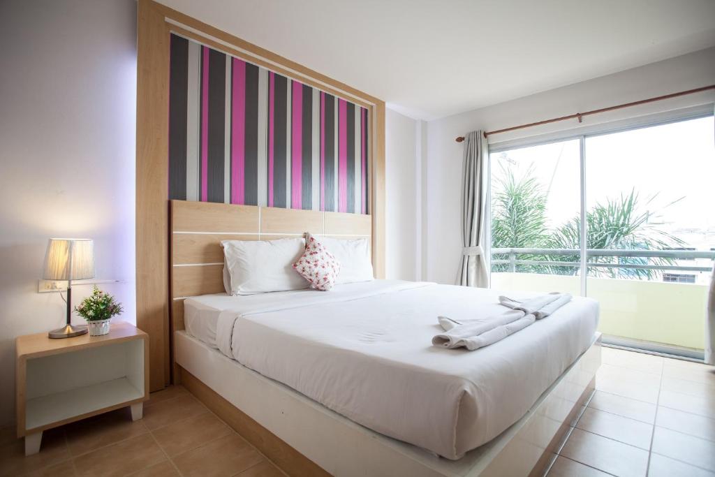 - une chambre avec un grand lit et une grande fenêtre dans l'établissement The Greenery Hotel, à Krabi
