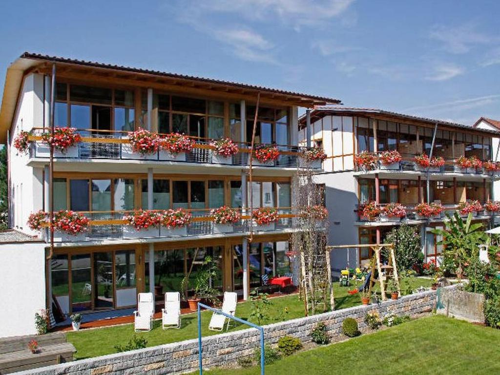 un grand bâtiment avec des boîtes de fleurs sur les balcons dans l'établissement Appartement Hotel Seerose, à Immenstaad am Bodensee