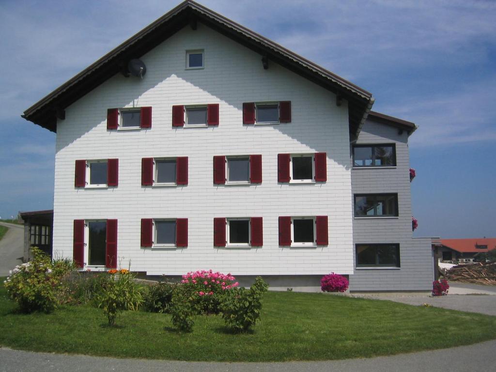 Hof Lässer في Möggers: منزل أبيض كبير مع نوافذ مغلقه حمراء