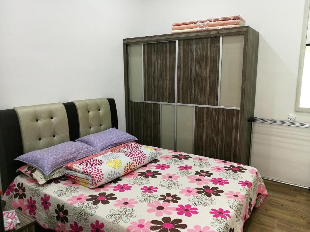 een slaapkamer met een bed met een bloemenbed bij Barakah Homestay in Alor Setar