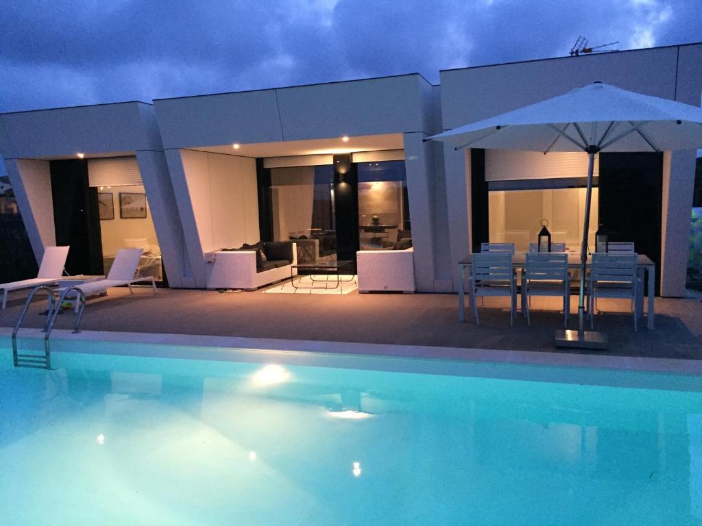 uma piscina com cadeiras e um guarda-sol ao lado de uma casa em Casa de lujo frente a la playa de Es Trenc em Sa Ràpita