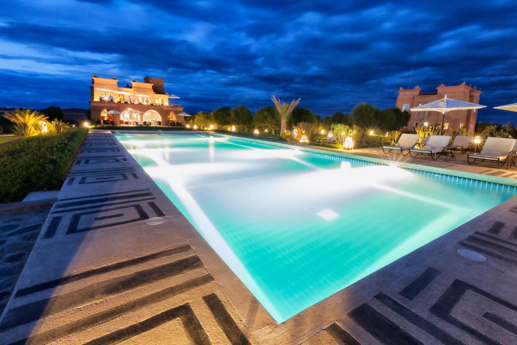 - une piscine la nuit avec une villa en arrière-plan dans l'établissement Sultana Royal Golf, à Afeggou