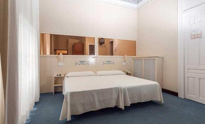 1 dormitorio con 1 cama blanca grande y espejo en Hotel Ramona, en Laredo