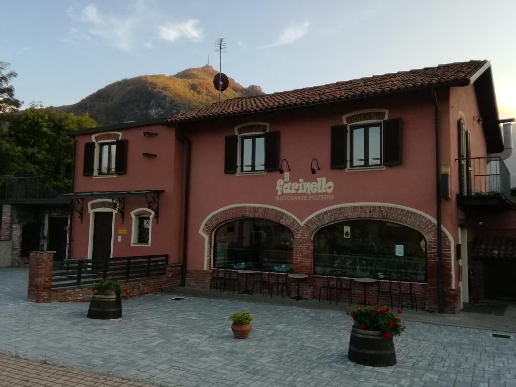 a red building with a mountain in the background at Guest House " IL FARINELLO " in Garessio