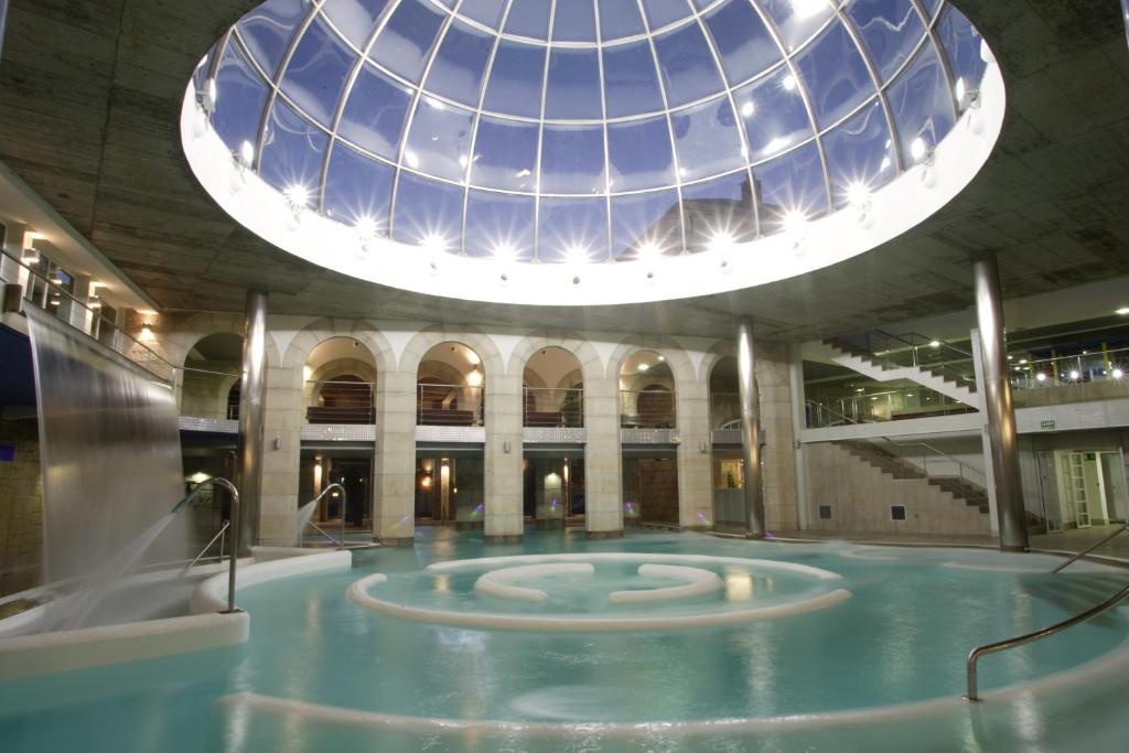 蒙達里斯－瓦爾內亞里奧的住宿－孟達利茲浴場酒店，一座带玻璃圆顶的建筑中的游泳池