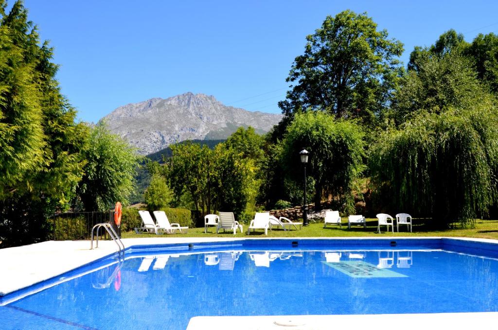 a swimming pool with chairs and a mountain in the background at Hotel Infantado in Ojedo