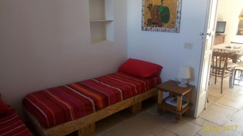 オストゥーニにあるcasa miaの赤毛布付きのドミトリールームのベッド1台分です。