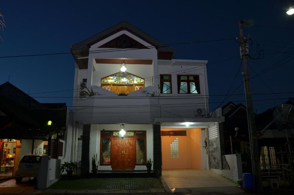 a white house with a front door at night at Surya Darma Homestay in Yogyakarta