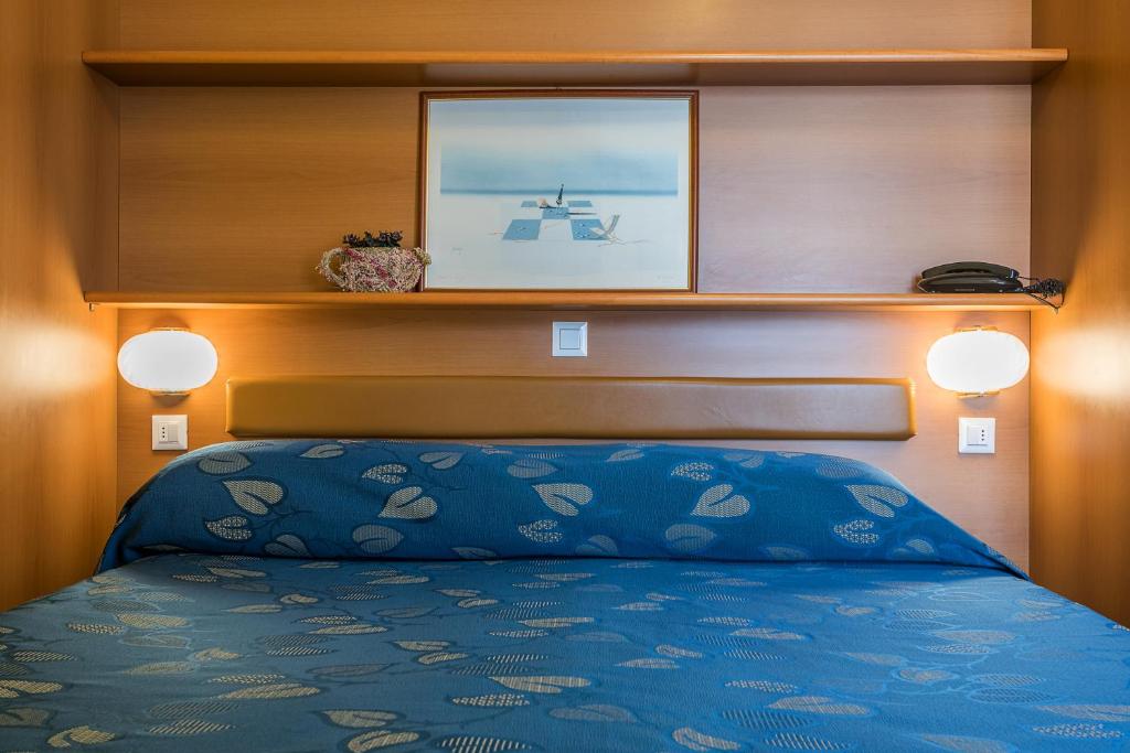 a bedroom with a bed with a blue bedspread at Hotel Calypso in Ventimiglia