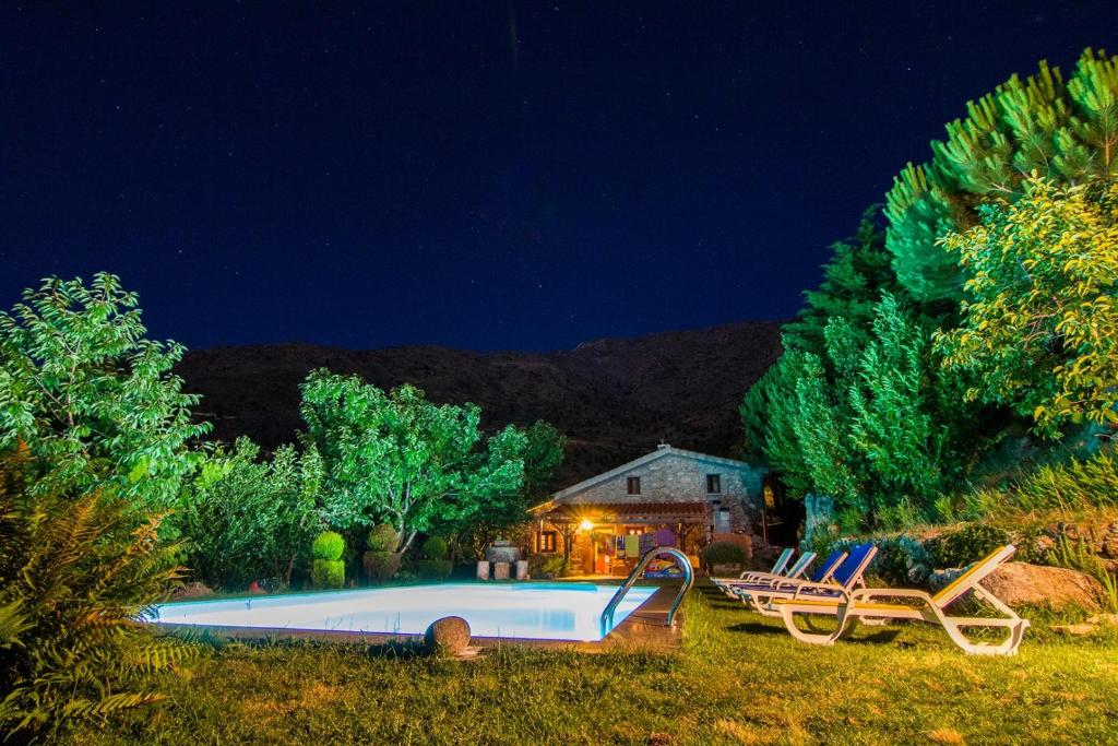 uma piscina com duas cadeiras e uma casa  noite em Quinta Do Circo - Serra Da Estrela - Turismo Rural em Cortes do Meio