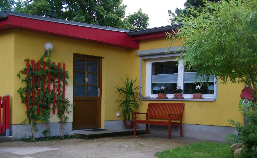 une maison jaune avec un banc rouge devant elle dans l'établissement Ferienwohnung mit Garten, à Berlin