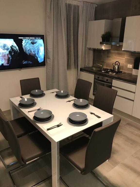 een witte tafel met stoelen en een tv in de keuken bij Loft Sirmione in Sirmione