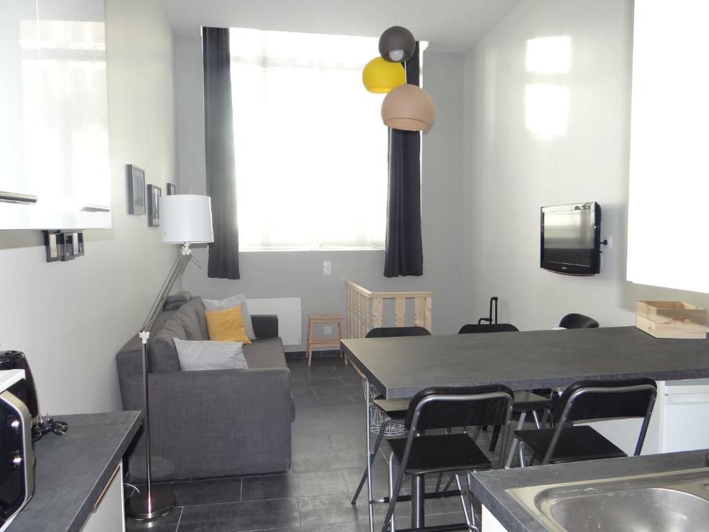 a living room with a table and a couch at Au détour des Places in Arras