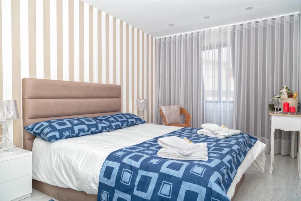 ein Schlafzimmer mit einem Bett mit einer blauen und weißen Decke in der Unterkunft BestVillas Âncora Praia in Vila Praia de Âncora