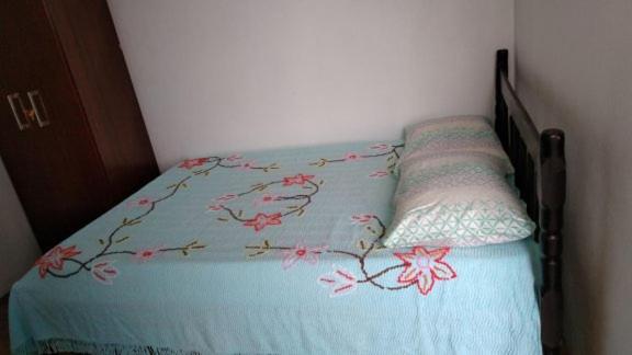 a bed with a blue comforter with flowers on it at Hospedagem Navegantes in Navegantes