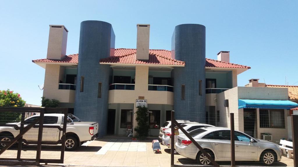 a building with cars parked in front of it at Sobrado Hibisco in Capão da Canoa