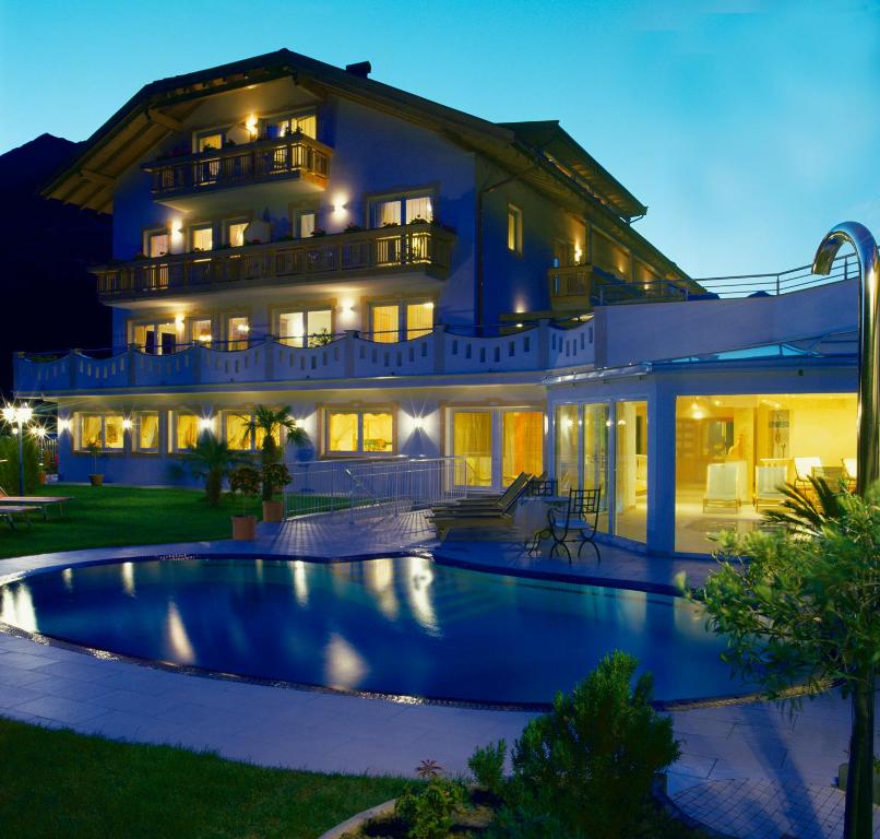 a large house with a swimming pool in front of it at Adults only Hotel Grafenstein in Schenna