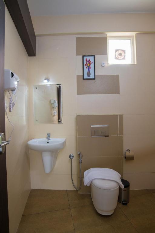 a bathroom with a toilet and a sink at Gems 9 Airport Hotel in Nedumbassery