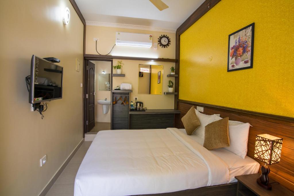 a bedroom with a white bed and a yellow wall at Gems 9 Airport Hotel in Nedumbassery