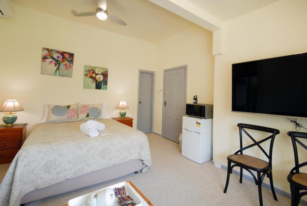
a hotel room with a bed, tv and a chair at Riverview Boutique Motel in Nambucca Heads
