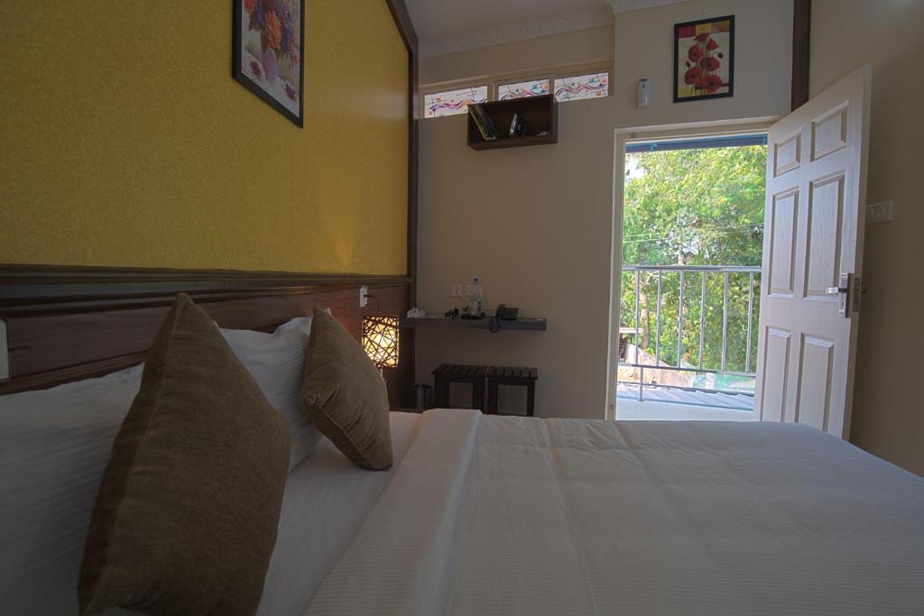 a bedroom with a white bed with a door open at Gems 9 Airport Hotel in Nedumbassery