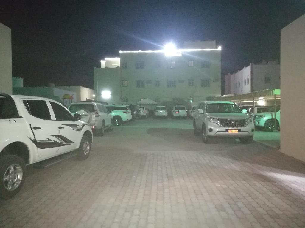 um parque de estacionamento com carros estacionados em frente a um edifício em Salassel Al Jabal Al Akhdar Guesthouse em Al ‘Aqar