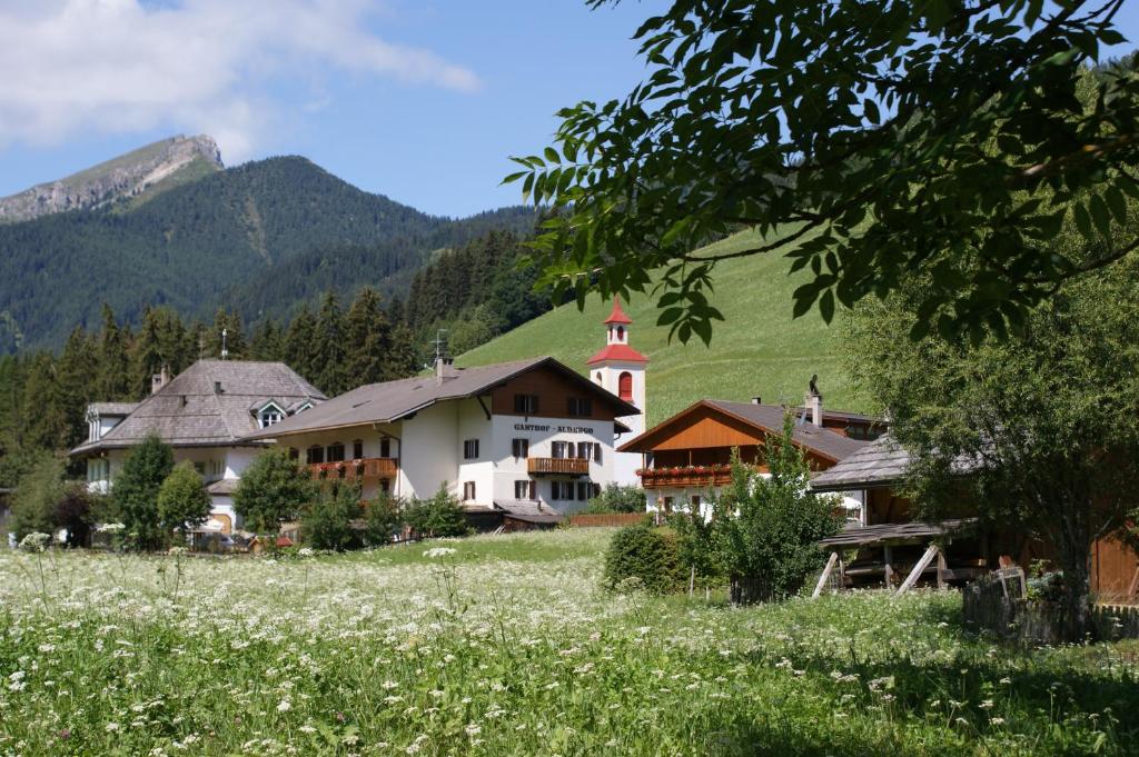 een dorp in de bergen met een bloemenveld bij Gasthof Huber in Braies