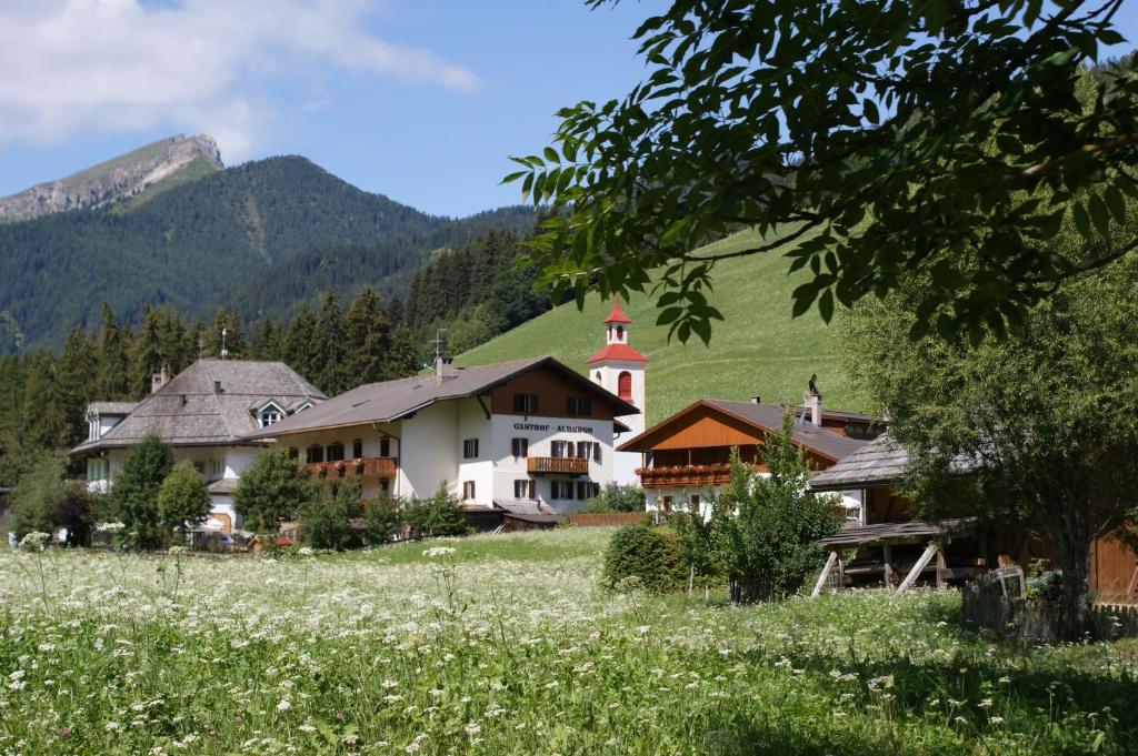 ein Dorf in den Bergen mit einem Blumenfeld in der Unterkunft Gasthof Huber in Prags