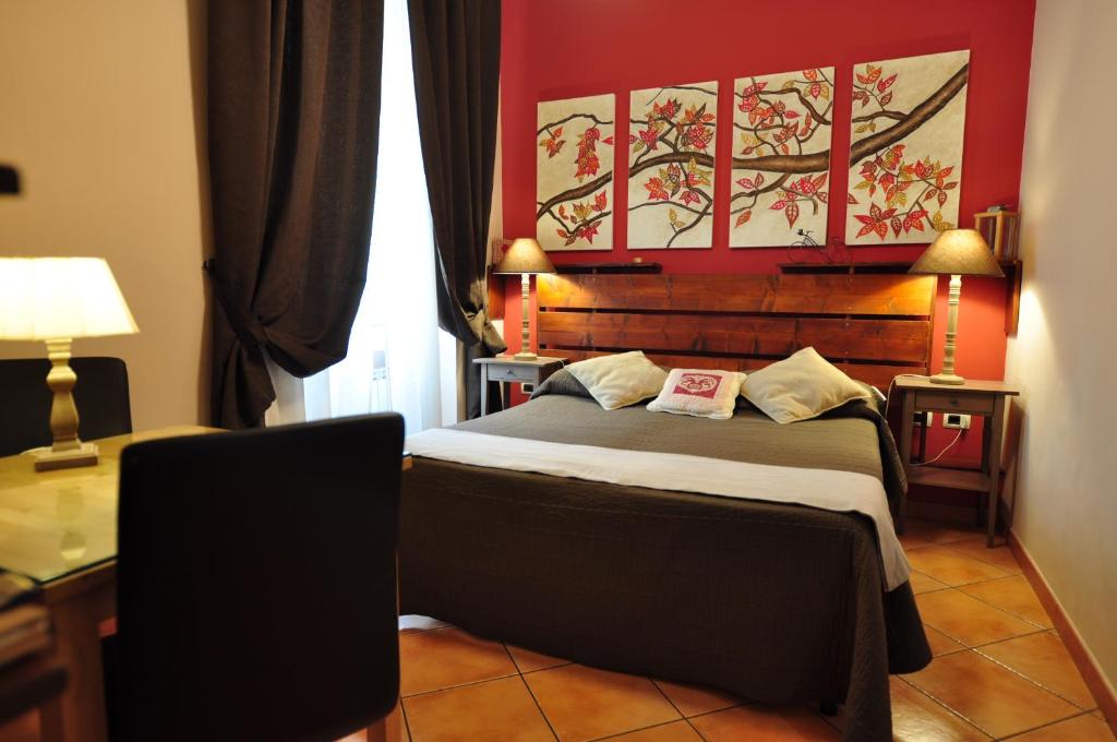 - une chambre dotée d'un lit avec un mur rouge dans l'établissement QuodLibet, à Rome