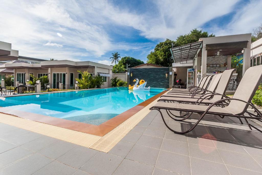 una piscina con 2 tumbonas junto a una casa en Thuan Resort en Rawai Beach