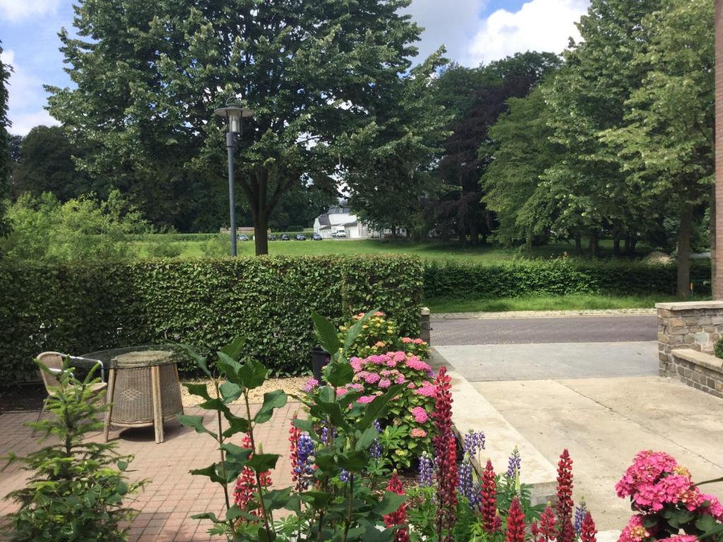 einen Garten mit Blumen und einer Bank in einem Park in der Unterkunft Belle Vue Vakantieappartement in Genoelselderen