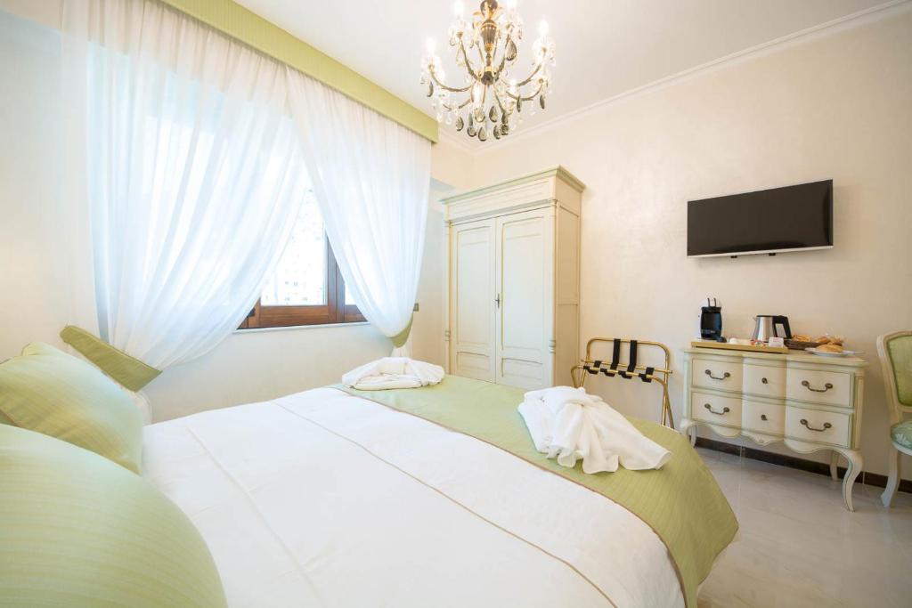 a bedroom with a large white bed with a chandelier at B&B Palazzo Montesanto in Maiori