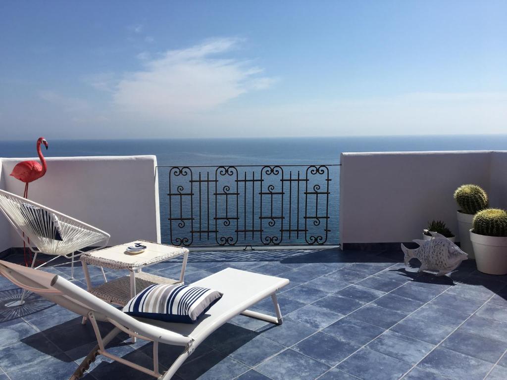 um pátio com cadeiras e uma mesa e o oceano em Paradiso Di Manù em Noli