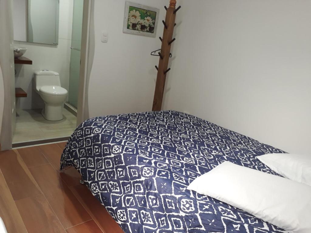 a bedroom with a bed with a blue and white comforter at Elizabetha Hostal in Salento