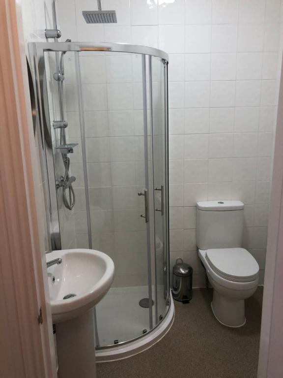 a bathroom with a shower and a toilet and a sink at Good Intent Rooms in Waltham Abbey