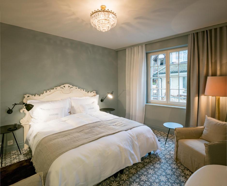 a bedroom with a bed and a chair and a chandelier at La Couronne Atelier - Dependance in Solothurn