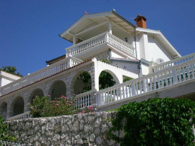 una casa blanca con una barandilla blanca y una valla en Villa I Karma, en Tisno