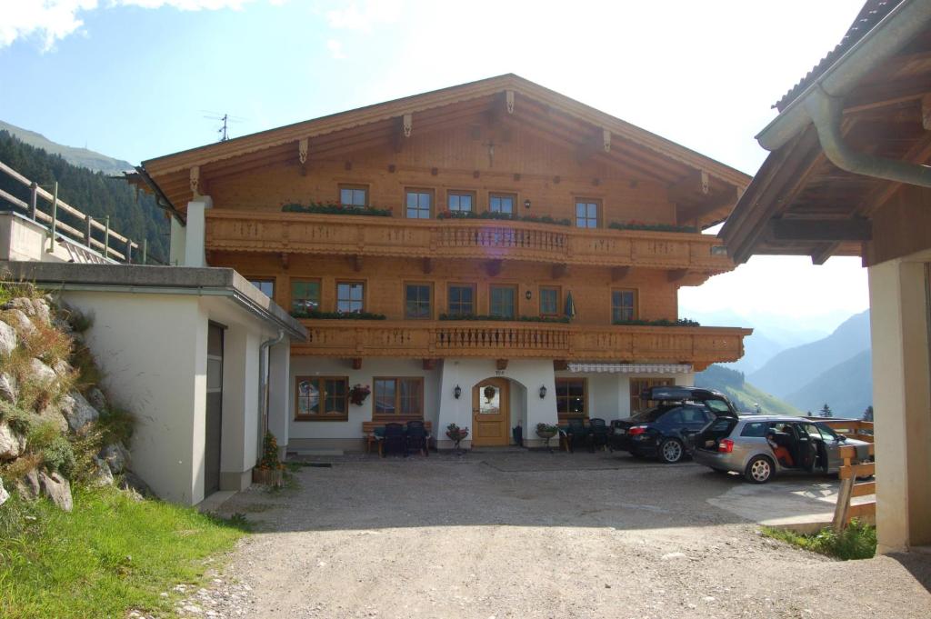 un grand bâtiment avec des voitures garées devant lui dans l'établissement Honsnhof, à Tux