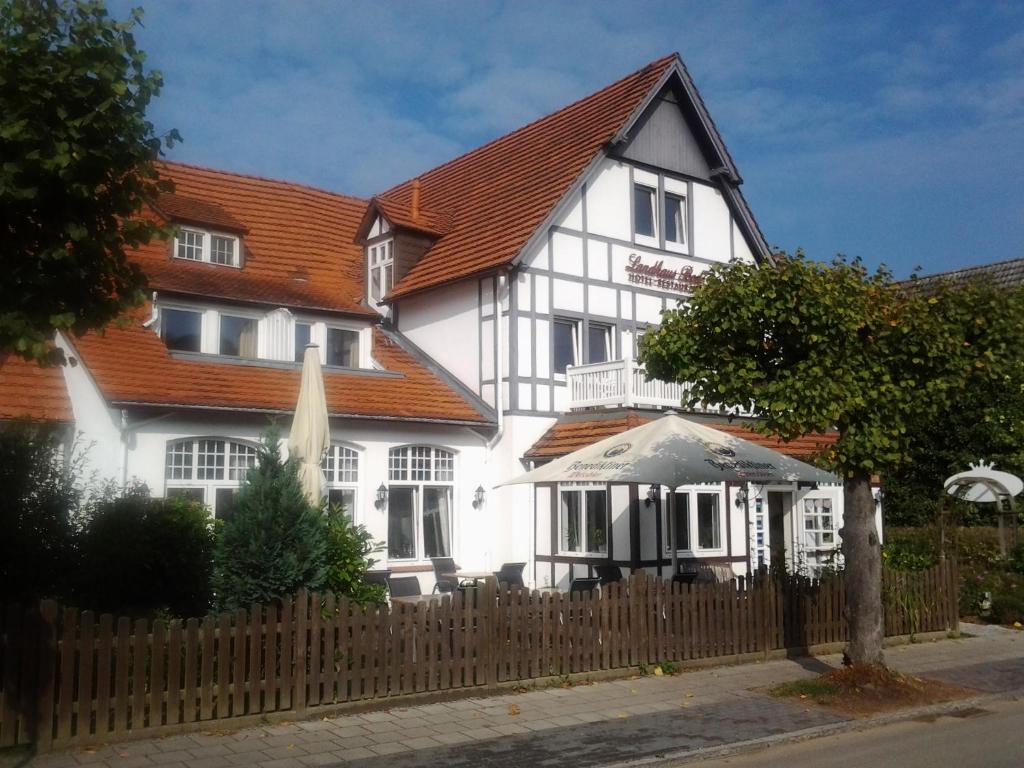 un bâtiment blanc avec une clôture en bois devant lui dans l'établissement Landhaus Bode, à Travemünde