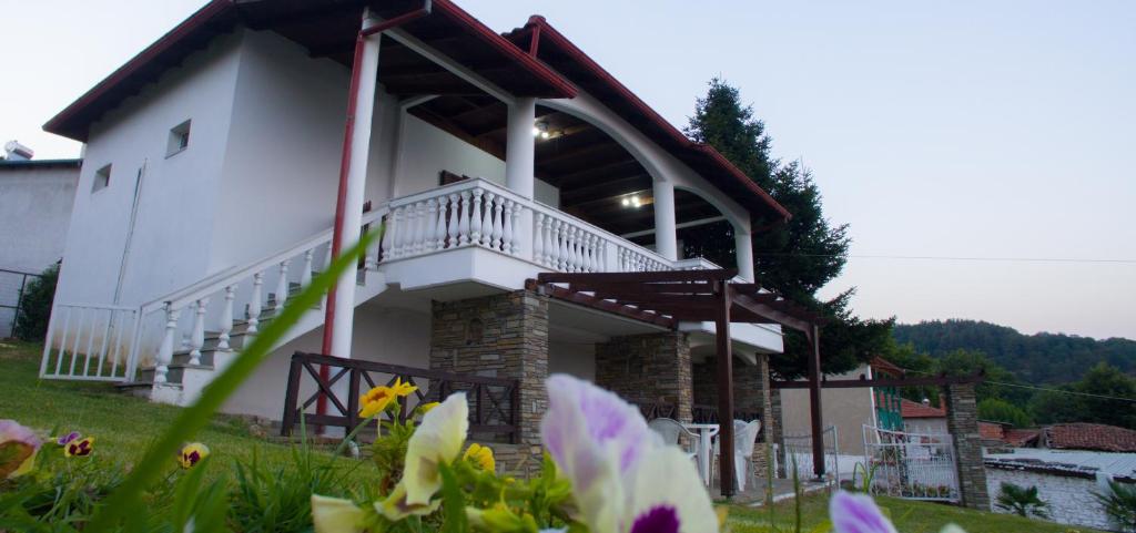 - un grand bâtiment blanc avec un balcon et des fleurs dans l'établissement Villa Paradisos, à Likóstomon