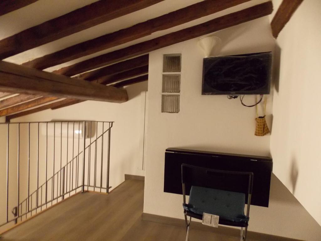 Zimmer mit einem TV und einem Stuhl in einem Zimmer in der Unterkunft Il gatto con gli stivali suite - locazione turistica in Florenz