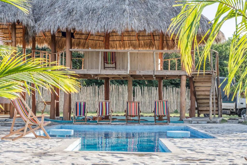 um resort com cadeiras e uma casa com telhado de palha em Ruamoko Hostel em Rivas