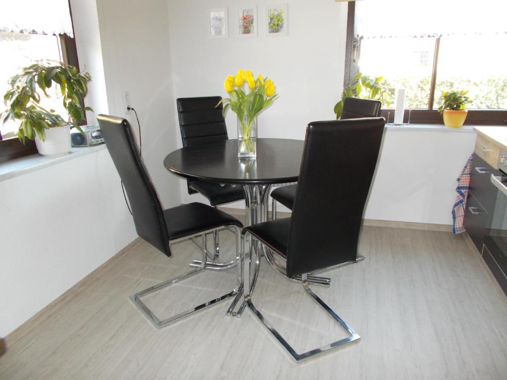 a dining room table with black chairs and a vase of flowers at Ferienwohnung Hoffmann in Rathmannsdorf