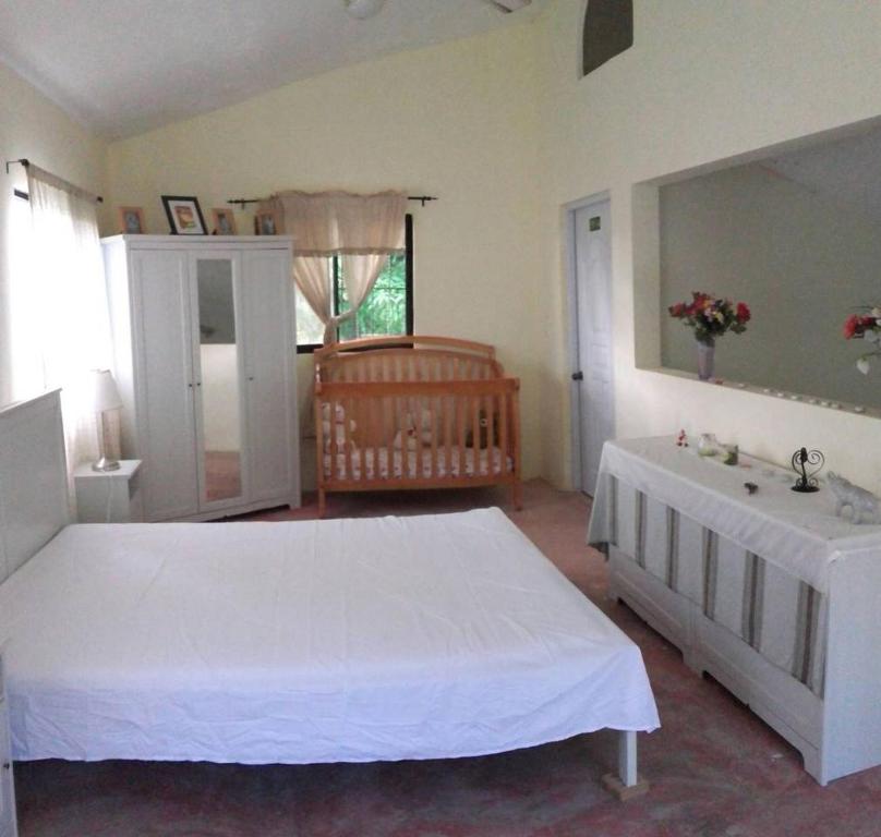 a bedroom with a large white bed and a sink at Hillside Country Home in Santa Bárbara de Samaná