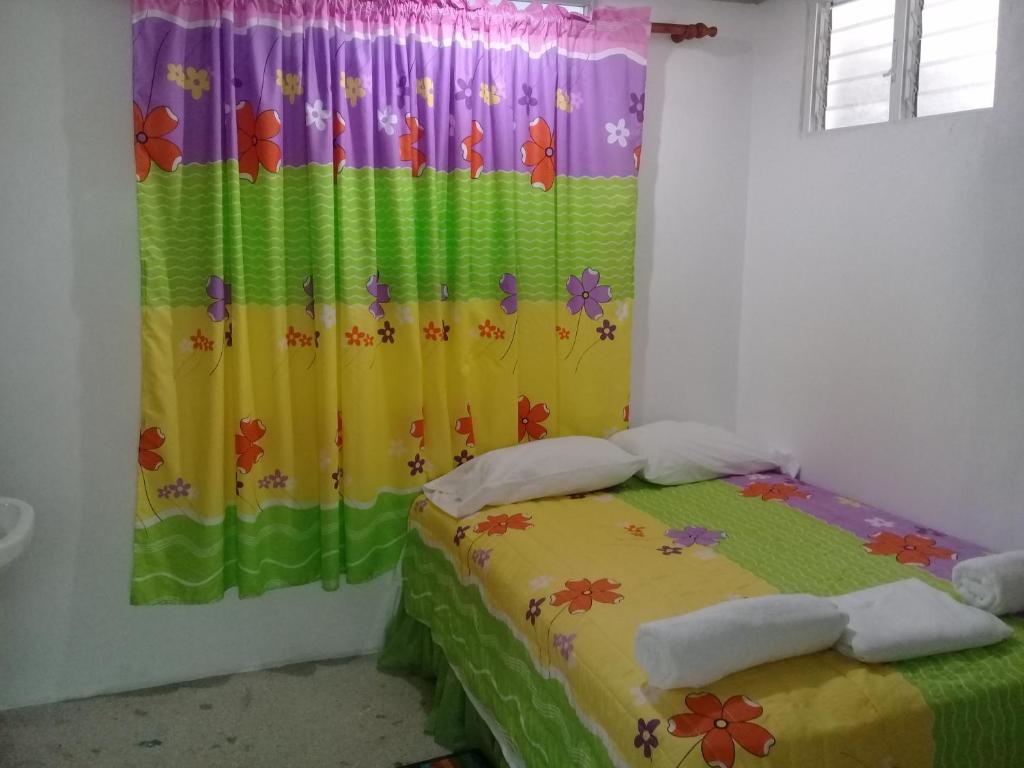 a bedroom with a bed with a colorful curtain at Hostel Quintonido in Jarabacoa