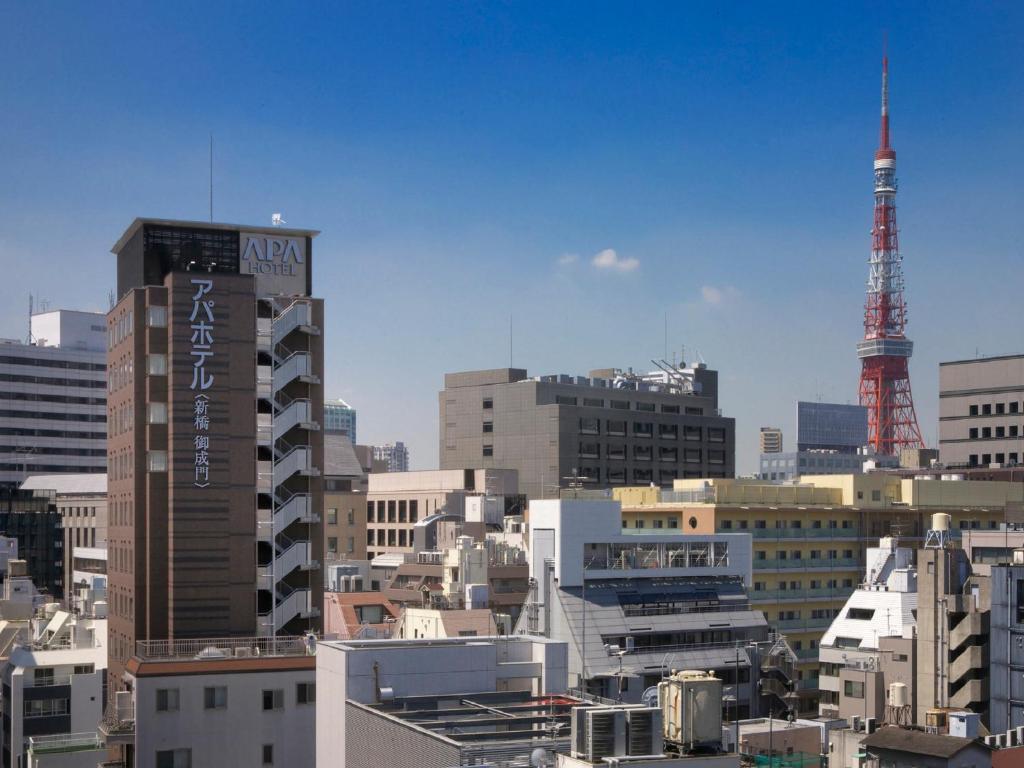 een skyline van de stad met hoge gebouwen en een rode toren bij APA Hotel Shimbashi Onarimon in Tokyo